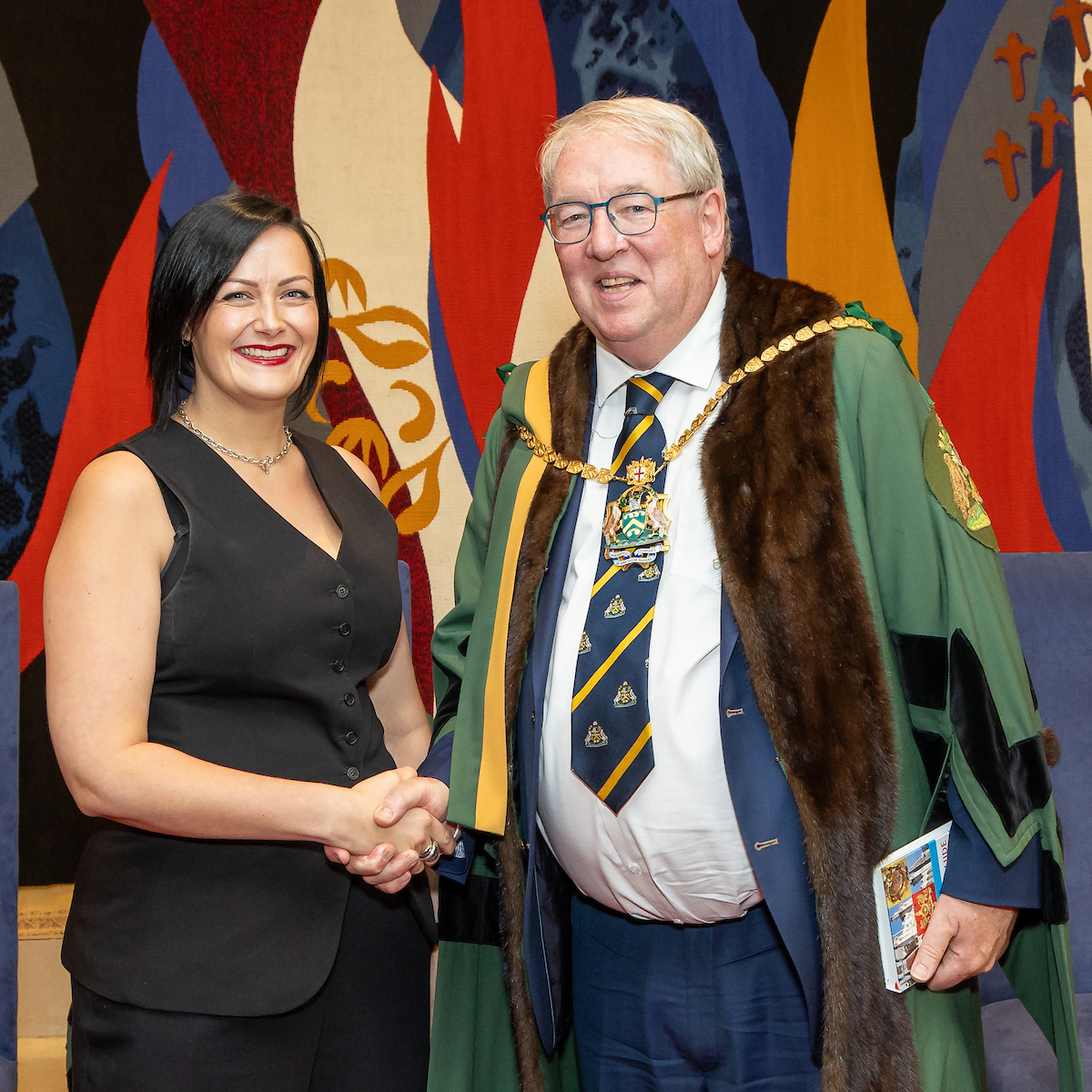 Freeman shakes hands with the Master, holding their Freedom certificate.