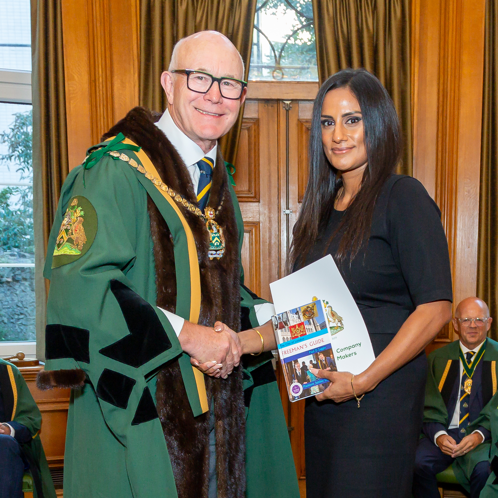 Freeman shakes hands with the Master, holding their Freedom certificate.